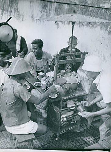 Гроздобер фотографија на клиенти кои јадат во мала количка за храна во град во Индонезија.